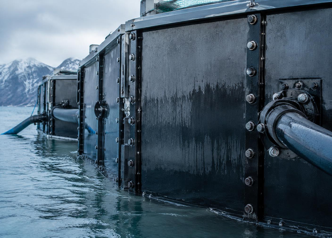 Close-up of a bolted marine-grade steel cage wall with deep-water intake piping